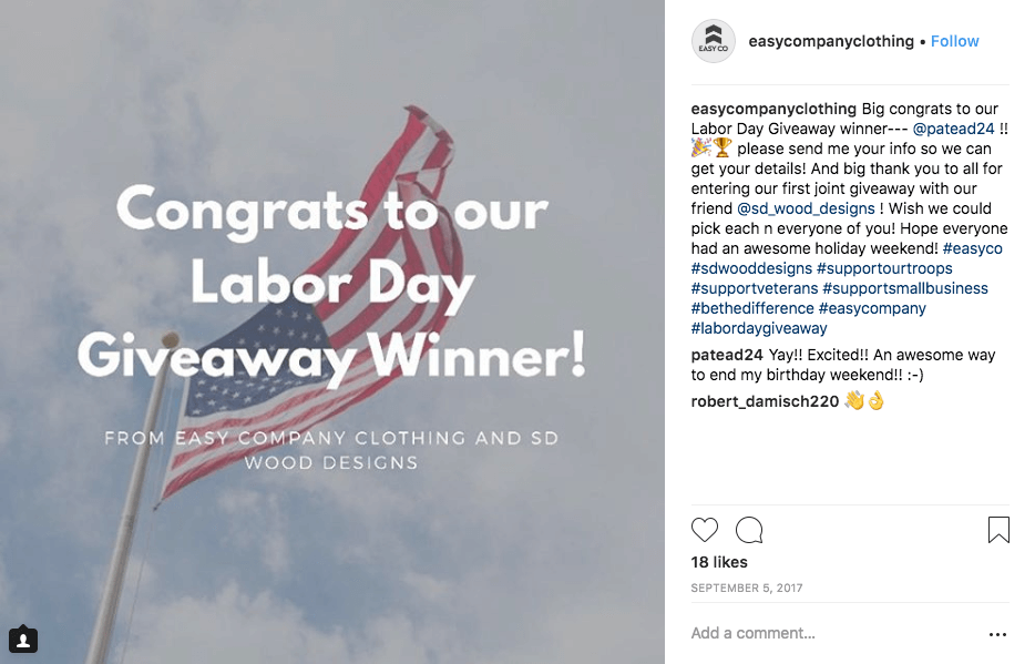 Instagram giveaways for Labor Day. The image shows a United States flag flying against a cloudy sky. The overlay text reads, "Congrats to our Labor Day giveaway winner! From Easy Company Clothing and SD Wood designs". The caption explains how the user can get in touch to claim their prize. The winner has commented on the post to say thank you.